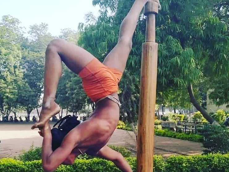 A bālasanyāsi in a Mallakhamba pole posture